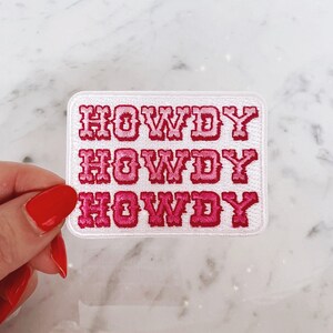 May include: White iron-on patch with the text "Howdy" repeated three times in pink and white embroidery.