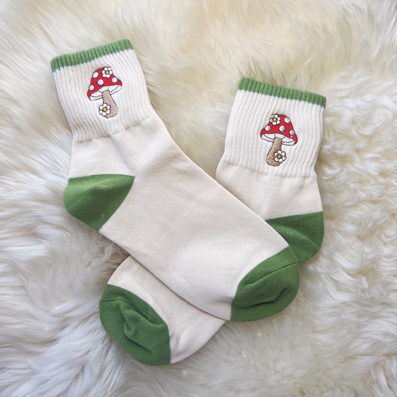 K&ouml;nnte beinhalten: Ein Paar wei&szlig;e Kn&ouml;chelsocken mit gr&uuml;nem Besatz und einer roten und wei&szlig;en Pilzembroiderie.