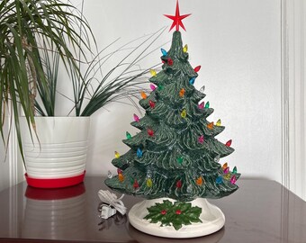 19 inch Lighted Ceramic Christmas Tree, multicolored bulbs. It has a white base with green holly and red berries.