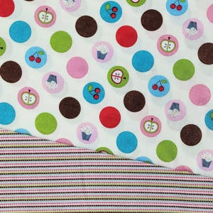 May include: Close-up of two fabric patterns. The top pattern is white with large, colorful polka dots and smaller circles with fruit and cupcake designs. The bottom pattern has thin, horizontal stripes in various colors.