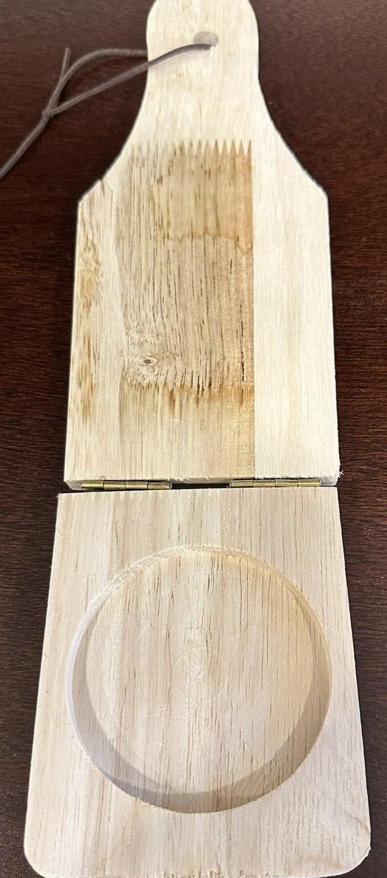 May include: A wooden hinged box with a round cutout in the bottom. The box is made of light wood and has a natural finish.