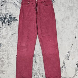 May include: A pair of burgundy colored jeans with a button fly.