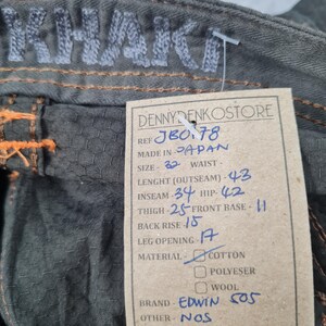 May include: Close-up of olive green denim pants with orange stitching. The word "KHAKI" is embroidered on the waistband. A tag reads "DENNYDENKOSTORE" and lists measurements: Outseam 43 inches, Inseam 34 inches, and Waist 32 inches. Brand is Edwin 505.