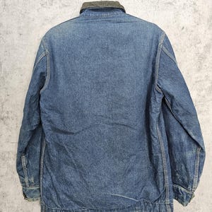 Puede incluir: Una chaqueta vaquera azul con cuello de pana. La chaqueta tiene mangas largas y cierre de botones.