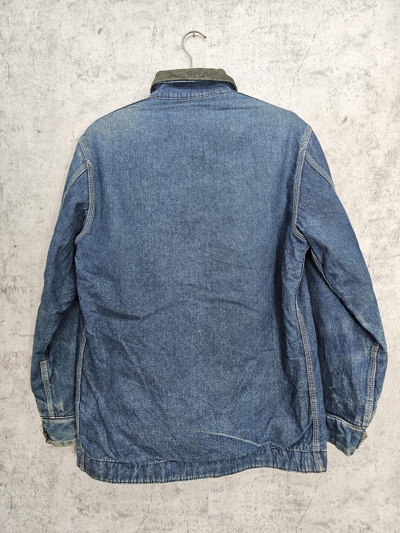 Puede incluir: Una chaqueta vaquera azul con cuello de pana. La chaqueta tiene mangas largas y cierre de botones.