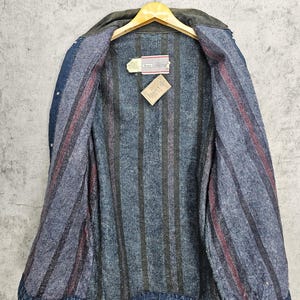 Puede incluir: Una chaqueta vaquera azul con forro de franela a rayas. La chaqueta tiene cierre de botones y dos bolsillos en la parte delantera. La etiqueta en el interior de la chaqueta dice "Scentsy".