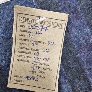 Puede incluir: Una etiqueta de papel marr&oacute;n con texto negro que detalla el tama&ntilde;o, las medidas y el material de una prenda. La etiqueta dice "DENNYDENKOSTORE", "REF-J0077", "MADE IN USA", "SIZE-M", "ARMPIT TO ARMPIT-22", "LENGHT-29", "SLEEVES LENGHT 24", "SHOULDER-18", "CONDITION-au/ RIP", "MATERIAL-COTTON", "POLYESTER", "WOOL", "NYLON", "BRAND-SEARS", "OTHER-".