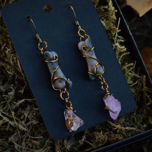 May include: A pair of earrings with a wire-wrapped grey and white stone and a pink crystal pendant.