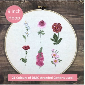 May include: A 9 inch embroidery hoop with six different floral designs embroidered on it. The flowers are pink, red, and white. The text "21 Colours of DMC stranded Cottons used." is at the bottom of the hoop.