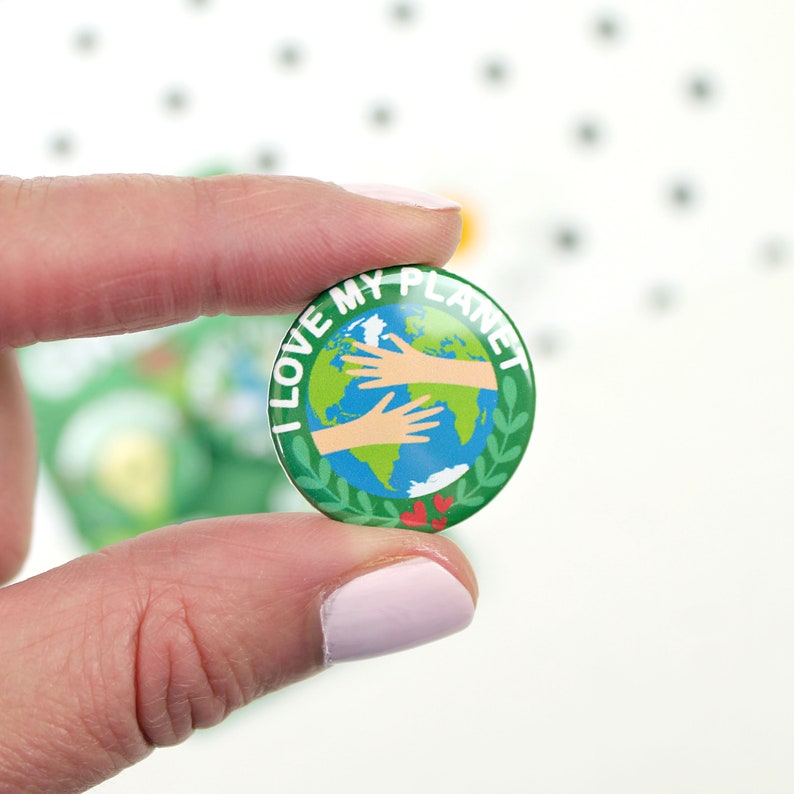 May include: A green button with the text "I Love My Planet" in white. The button features a cartoon image of the Earth with three hands reaching out to hug it.