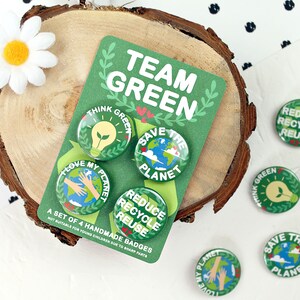 May include: A set of four green and white round pinback buttons with eco-friendly messages. The buttons say "Think Green", "Save the Planet", "Love My Planet", and "Reduce Recycle Reuse". The buttons are on a green card with the words "Team Green" in white.