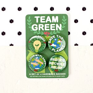 May include: Set of four green and white round pinback buttons with environmental slogans. The buttons say "Think Green", "Save the Planet", "I Love My Planet", and "Reduce Recycle Reuse". The buttons are packaged on a green card with the words "Team Green" in white.
