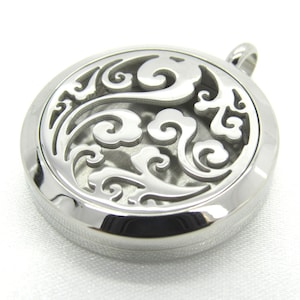 May include: A silver round pendant with a delicate, intricate design of swirling clouds and floral patterns. The pendant has a circular opening in the center, suggesting it is an aromatherapy diffuser.