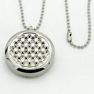 May include: A silver necklace with a round pendant featuring a flower of life design. The pendant is attached to a silver chain.
