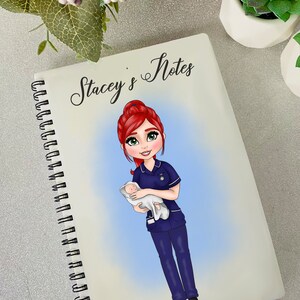 K&ouml;nnte beinhalten: Ein wei&szlig;es Spiralnotizbuch mit dem Text "Stacey's Notes" oben. Der Umschlag zeigt eine Comic-Illustration einer rothaarigen Frau in einer blauen Krankenschwesteruniform, die ein Baby h&auml;lt.