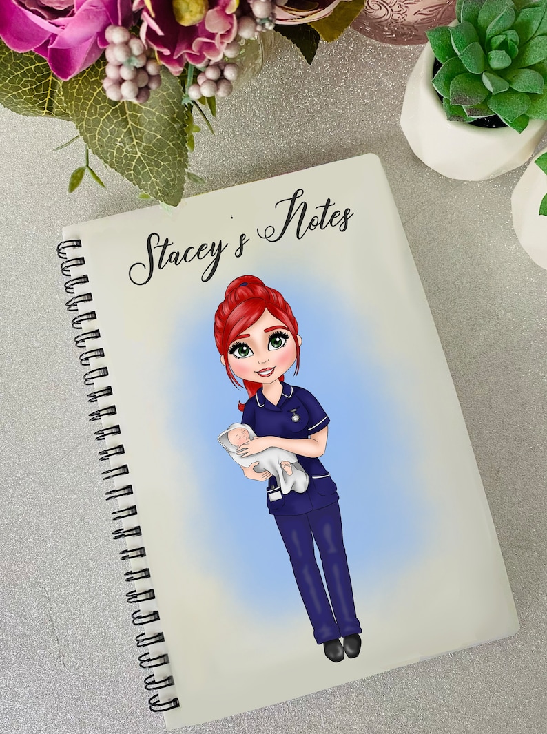 K&ouml;nnte beinhalten: Ein wei&szlig;es Spiralnotizbuch mit dem Text "Stacey's Notes" oben. Der Umschlag zeigt eine Comic-Illustration einer rothaarigen Frau in einer blauen Krankenschwesteruniform, die ein Baby h&auml;lt.