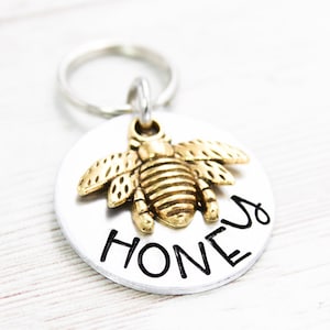 May include: Silver dog tag with a gold bee charm and the word "Honey" engraved on it.