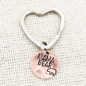 May include: A silver heart-shaped keychain with a copper penny charm that says "MAMA BEAR" with a small bear silhouette.