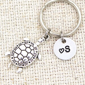 May include: Silver turtle keychain with a silver charm that says "S" with a heart above the letter.