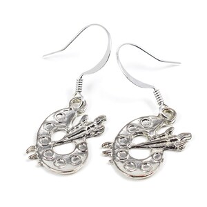 May include: Silver earrings with a paint palette and paintbrush design.