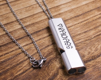 May include: A silver necklace with a silver whistle pendant. The whistle has the word "RADASS" engraved on it.