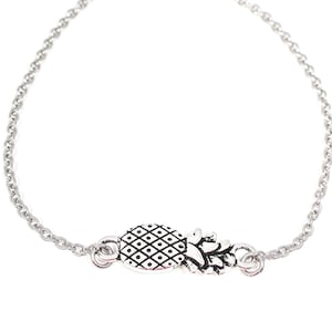 May include: A silver chain bracelet featuring a pineapple charm. The charm has a detailed textured pineapple design.