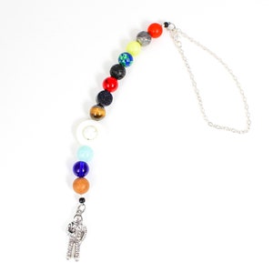 May include: A silver chain necklace with a silver astronaut charm and a beaded strand of colourful stones, including red, yellow, green, blue, and white.