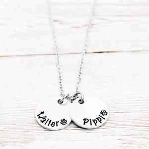 May include: Silver necklace with two round pendants. The pendants have the names "Walter" and "Pippi" engraved on them.