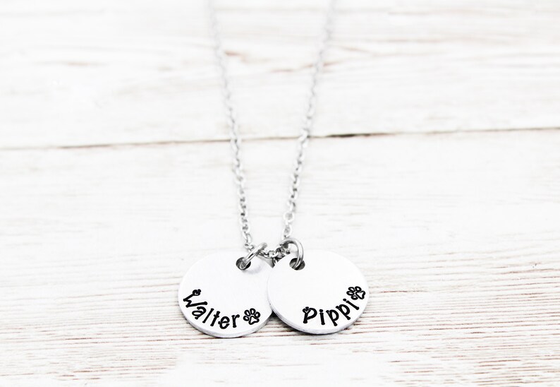 May include: Silver necklace with two round pendants. The pendants have the names "Walter" and "Pippi" engraved on them.