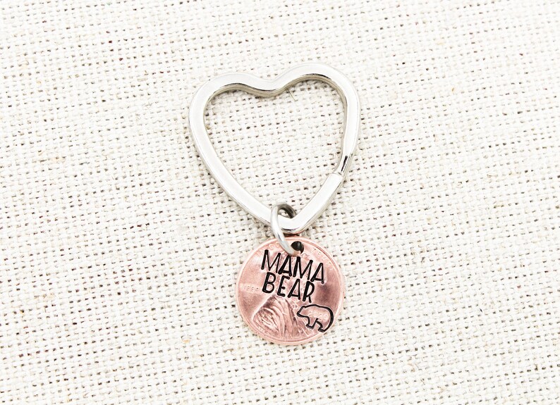 May include: A silver heart-shaped keychain with a copper penny charm that says "Mama Bear" with a small bear silhouette.