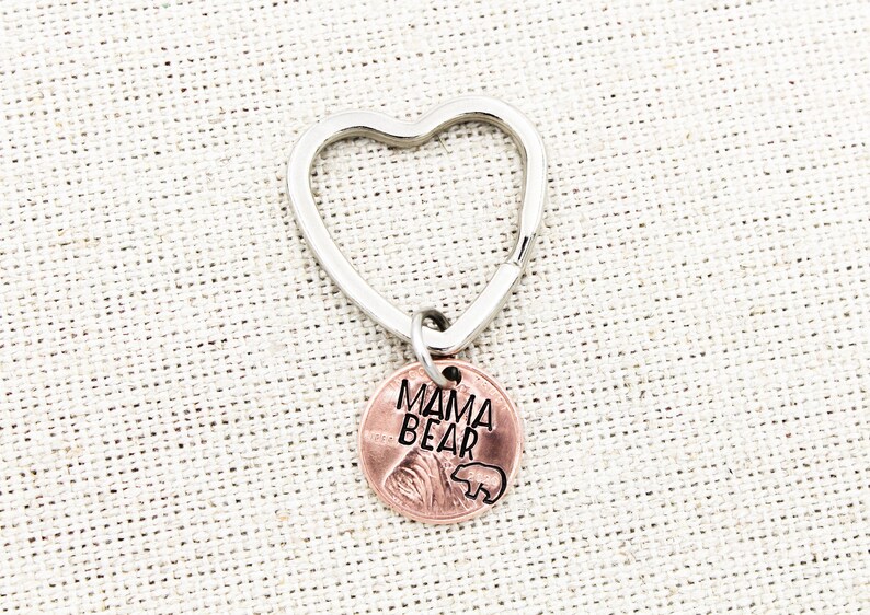 May include: A silver heart-shaped keychain with a copper penny charm that says "Mama Bear" with a small bear silhouette.