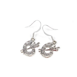 May include: Silver dangle earrings featuring a paint palette with a paintbrush design.