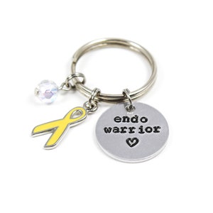 May include: A silver keychain with a yellow ribbon charm, a crystal bead, and a silver charm with the text "endo warrior" and a heart.