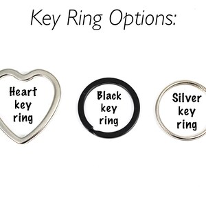 May include: Three key ring options: a silver heart-shaped key ring, a black circular key ring, and a silver circular key ring. Each key ring has the words "key ring" printed on it.