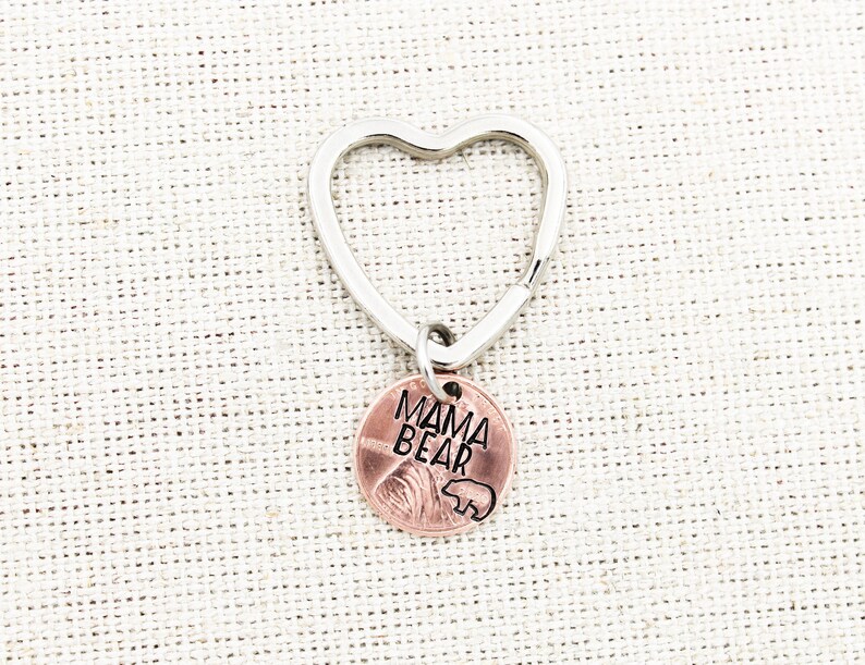 May include: A silver heart-shaped keychain with a copper-colored charm that says "Mama Bear" with a small bear silhouette.