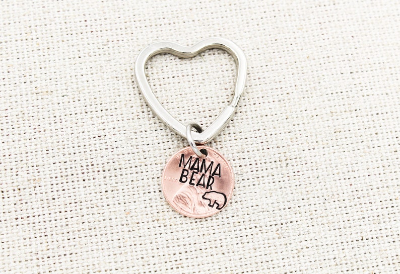 May include: A silver heart-shaped keychain with a copper penny charm that says "MAMA BEAR" with a small bear silhouette.