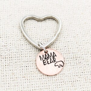 May include: A silver heart-shaped keychain with a copper-colored charm that says "Mama Bear" with a small bear silhouette.