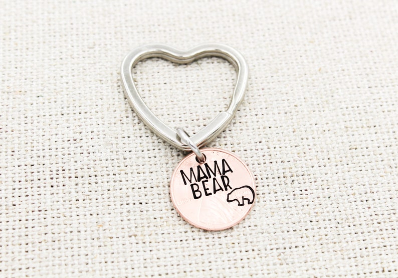May include: A silver heart-shaped keychain with a copper-colored charm that says "Mama Bear" with a small bear silhouette.