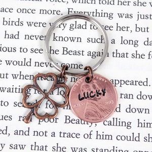 May include: A copper penny keychain with the word "LUCKY" inscribed on it. The keychain also features a four-leaf clover charm.