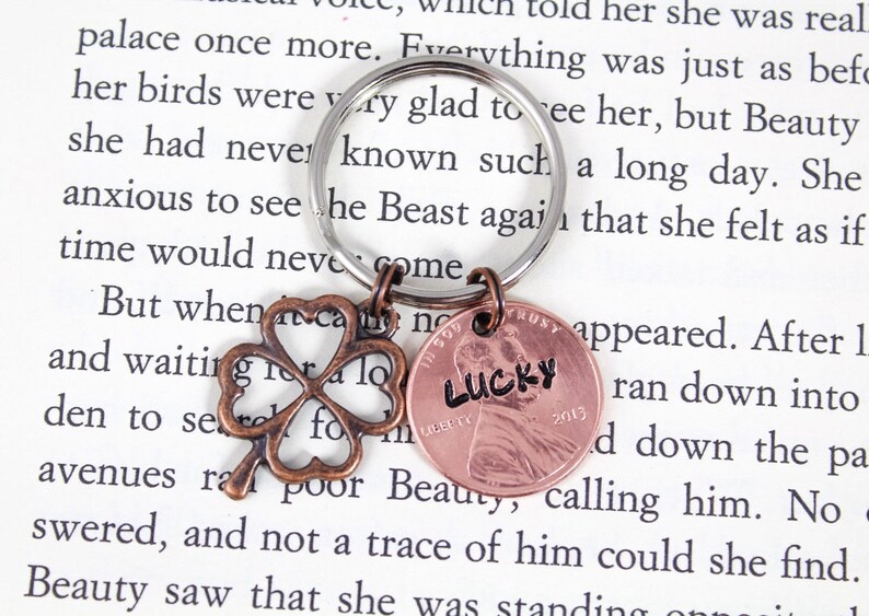 May include: A copper penny keychain with the word "LUCKY" inscribed on it. The keychain also features a four-leaf clover charm.