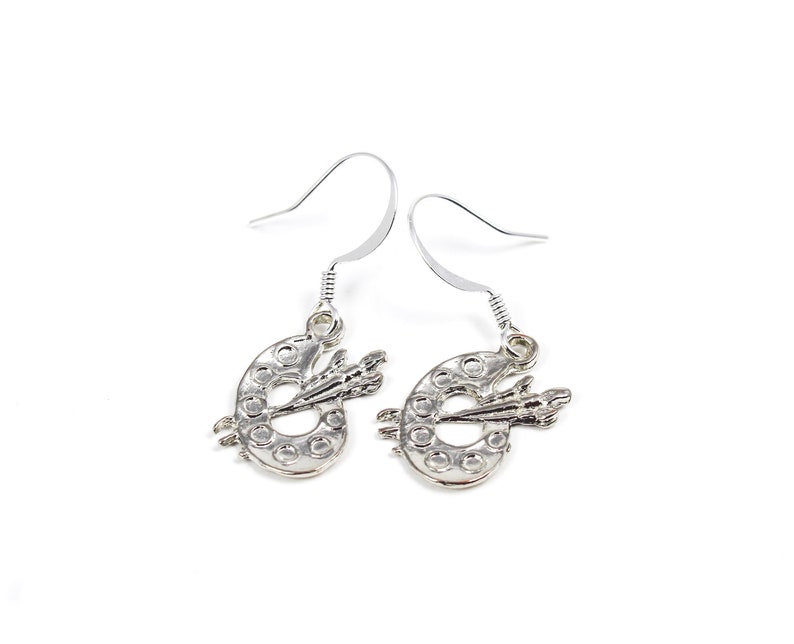 May include: Silver earrings with a paint palette and paintbrush design.