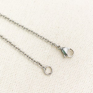 Puede incluir: Un collar de cadena de plata con un cierre de langosta y un anillo de salto.