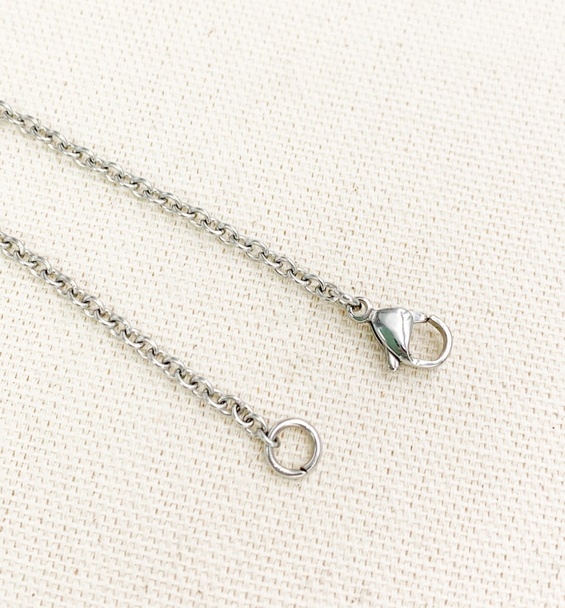 Puede incluir: Un collar de cadena de plata con un cierre de langosta y un anillo de salto.