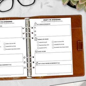 May include: Open planner with brown leather cover, featuring pages for tracking avoidance and excuses. The pages include sections for listing avoided responsibilities, an avoidance level tracker, and a space for listing excuses. The planner is designed for professional excuse-makers.