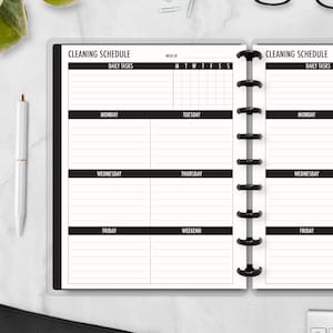 May include: Open planner with a black cover and a cleaning schedule layout. The schedule is divided into daily tasks, with sections for each day of the week, including the weekend. The text "CLEANING SCHEDULE" is at the top.