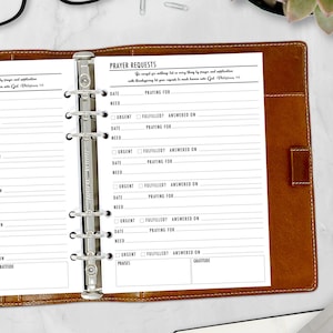 May include: A white paper insert for a ring binder, featuring a "Prayer Requests" template. The template includes sections for date, prayer requests, and checkboxes for urgency and fulfillment. The binder is brown.