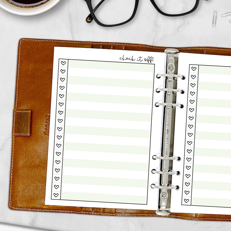 Printed A5 Check It Off checklist planner insert in Celery shown in a tan leather ring binder on a marble desk. Green striped design with heart checkboxes. Physical paper insert only -- binder and accessories not included. Planner insert is made in the USA by CityGirl Planners.