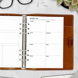 May include: A weekly planner with a brown leather cover and a silver binder. The planner has a gridded section on the left and a weekly schedule on the right. The weekly schedule is divided into days of the week, with space for writing tasks and appointments.
