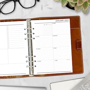 May include: A brown leather bound planner with a silver ring binder. The planner is open to the January 2028 page, which has a grid for daily notes and a weekly calendar.