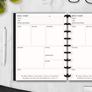 May include: A white Bible study planner with black binding and a pen. The planner has sections for passage, theme, outline, word study, and application. The text "BIBLE STUDY" is at the top of each page. The bottom of the page has a Bible verse.